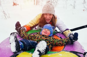 69070359 - happy smiling mother and child sit on snow tube winter activities