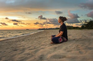 meditation benefits for brain 41846180 - woman sitting on beach sand and relaxing at sunset time